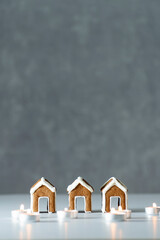 Tasty glazed painted gingerbread houses and candles on gray background. Vertical frame. Copy space