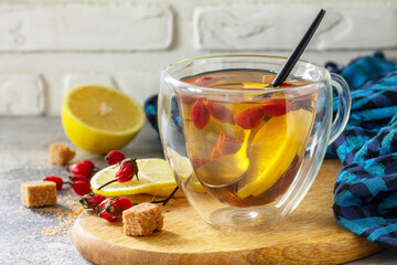 Vitamin winter drink. Hot tea rosehip dried with honey and lemon on a wooden table top.