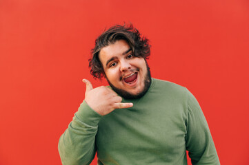 Funny cheerful bearded overweight hispanic man is imitating a calling gesture, being positive, opening his mouth. Communication concept, isolated background.