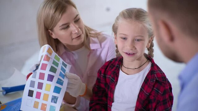 family time together with daughter during apartment renovation, couple and kid girl with palette choose colors for painting the wall in new house