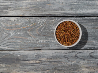Cereal of buckwheat in the bowl on wooden background.