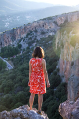 Naklejka premium A girl in a red dress on a large rock on top of a mountain