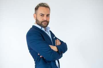 Young man wearing suit with arms folded looking at camera over white background.