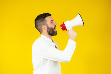 Man yelling into a megaphone over yellow background.