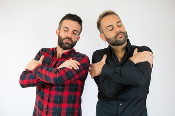 Young gay couple of two men wearing casual clothes hugging oneself happy and positive, smiling confident. self love and self care