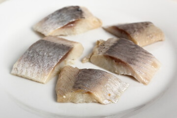 Pickled herring on plate. Salted, soused skinless slices of fish Clupea.