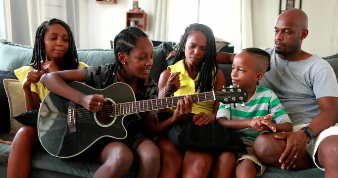 Family enjoying music together, joyful African black parents and children bonding together