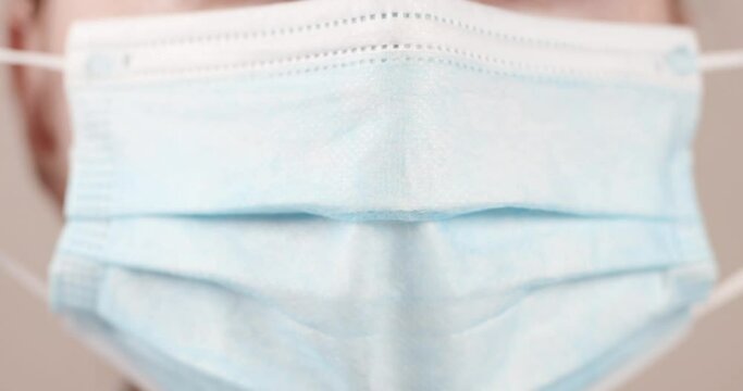 Remove dirty medical mask correctly during covid-19 coronavirus pandemic. Close up shot of female face mouth wears protective medical mask and blue surgical rubber gloves in clinic laboratory