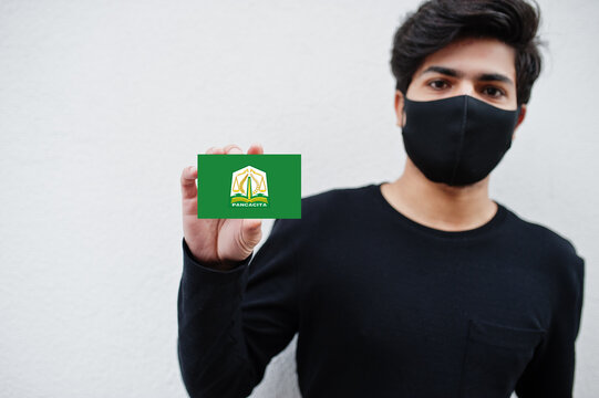 Indonesian man wear all black with face mask hold Aceh flag in hand isolated on white background. Provinces of Indonesia coronavirus concept.