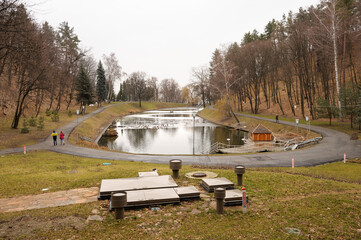 Fototapeta na wymiar Pond, park and arbour, people walking around. Mezhygyhirya, Ukraine