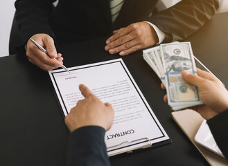 Hands of businessmen agreeing to the offer of bribery by signing a personal benefit agreement The concept of fraud and business practices within the company