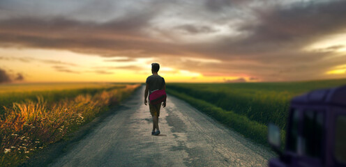 Obraz premium a young man on a road trip in the open valley at sunset landscape.