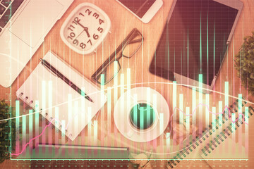 Double exposure of financial chart hologram over desktop with phone. Top view. Mobile trade platform concept.