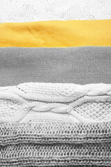 Knitted clothes gray and yellow background. Trending colors 2021 yellow and gray