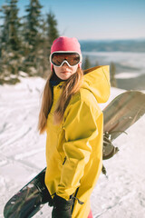 Woman with mask for snowboarding with mountains covered by snow in background. Girl skier wearing...