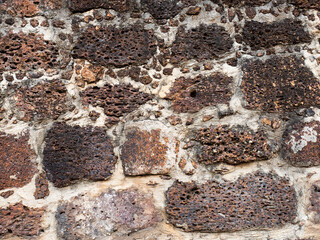 Old wall made of perforated brick, small and large bricks are laid out in a mess. 