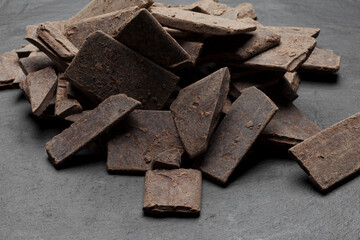 Raw 100% pure organic cocoa chocolate bar isolated on black stone background with shadow. Theobroma cocoa mass or paste