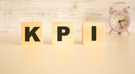 The word KPI consists of wooden cubes with letters, top view on a light background.