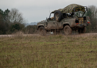 roofless british army land rover 4x4 Wolf with camouflage tarpaulin rear in action on military exercise, Wiltshire UK 
