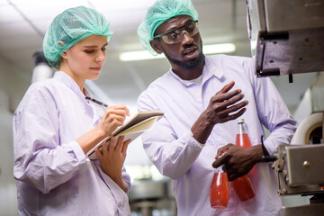 Quality control woman and man wearing a lab coat to checking juice industrial process at factory. Teamwork at production line successful concept.
