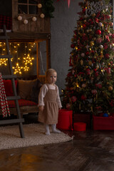 a little girl stands near a Christmas tree with toys