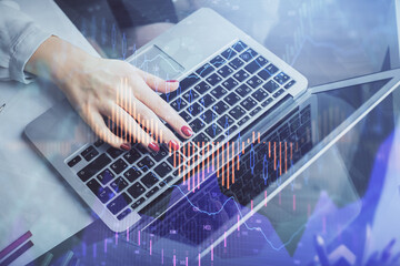 Double exposure of businesswoman hands typing on computer and financial graph hologram drawing. Stock market analysis concept.