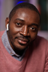 Close-up of African confident businessman in wireless headphones looking at camera