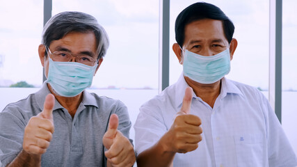 Two senior men wearing protective face masks during quarantine at home.