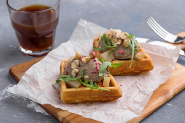 Belgian waffle with liver pate and hazelnut and glass of coffee on gray background