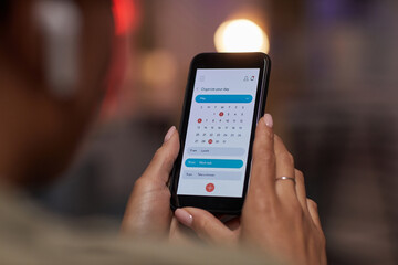 Close-up of woman using online calendar on mobile phone to plan her week