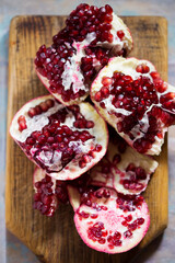 Pomegranate cut into pieces on wooden board 