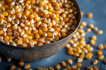 Dried corn in old bowl on blue background.