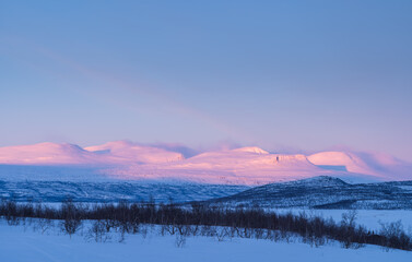 Mountains in the last, pink, sunlight of a winters day. Lapland, Sweden