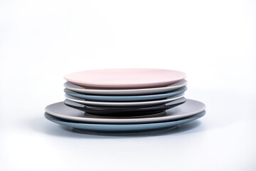 Stack of seven Large and Small colorful empty plates isolated on white background, side view. Navy Blue, Grey, Black, White, and Pink empty plates collection