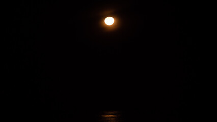 moonlight reflections on sea. Full moon setting on horizon in ocean with reflection shining.