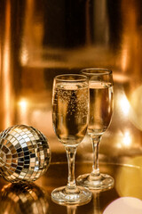 Glasses of champagne and a disco ball on a shining gold background