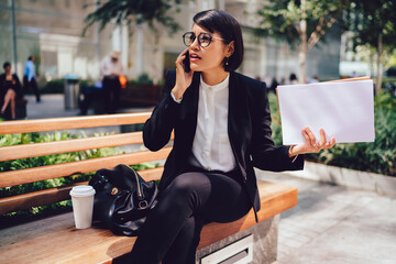 Dissatisfied businesswoman talking on smartphone on bench