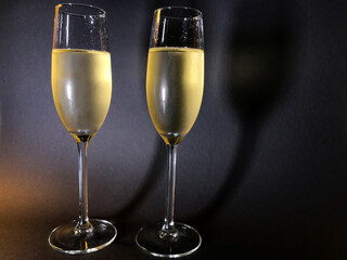 Cold champagne in two stylish glasses, bubbles, in sparkling wine, concept of new year, celebration, romantic. Black background, whole figure glasses closeup shot, thin vapor on glasses
