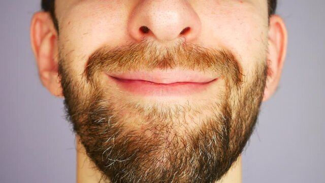 A bearded man with a wave of his hand changes his face from normal to smiling close-up