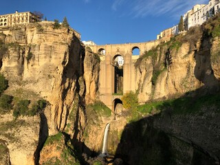 Big bridge wall with waterfall stream and city on top