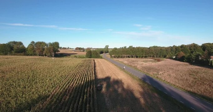 Quad Bike Driving on a Field Next to a Road on a Sunny Autumn Afternoon in South Sweden Sk&aring;ne &Ouml;sterlen, Aerial Descending Following Shot