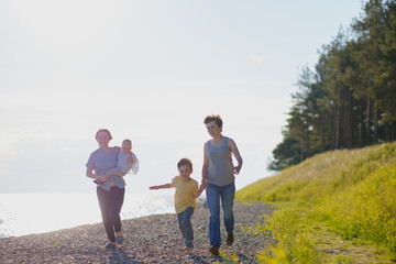 Homosexual lesbian family with two children, a son and a daughter. Two moms and kids at an outdoor picnic. Forest and sea.