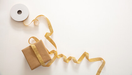 Christmas gift box and golden ribbon on white background, top view.
