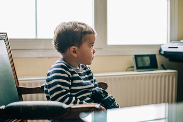 Curious child explores camera sitting on a chair