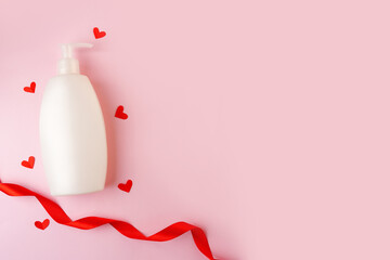 Cosmetics, shampoo Bottle with red hearts and ribbon on pink background with copy space. valentine's day, skin care with love
