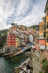 Fototapeta na wymiar Cloudy day in Riomaggiore, panoramic landscapes of Riomaggiore with its cliff and port beside the sea
