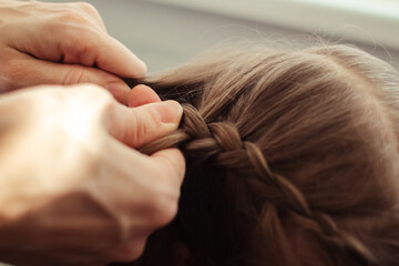 Fototapeta premium Mom is combing her daughter's hair. Taking care of baby's hair. The concept of a happy childhood and a good attitude towards children. Happy family