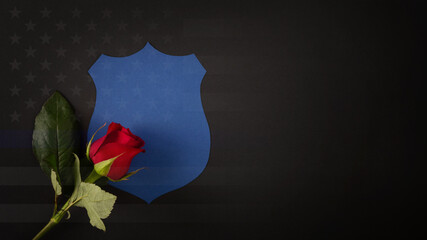 Blue shield with a red rose draped across it. National Law Enforcement Officers Memorial Fund symbol