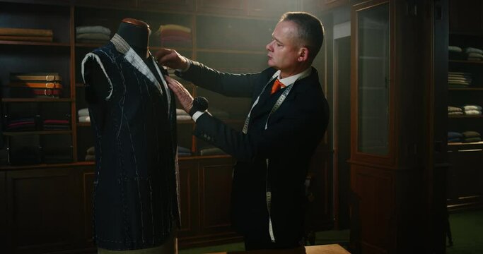 Cinematic shot of professional tailor taking measurements for creation of custom high quality tailored suit in luxury tailoring atelier.Concept of fashion, handmade, hand craft, couturier and business