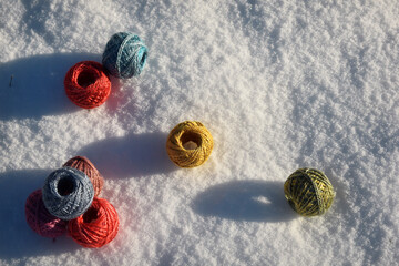 Obraz na płótnie Canvas little balls of wool, silk yarn in the snow in sun, colorful in red, blue, yellow, green, purple, background for knitting, weaving